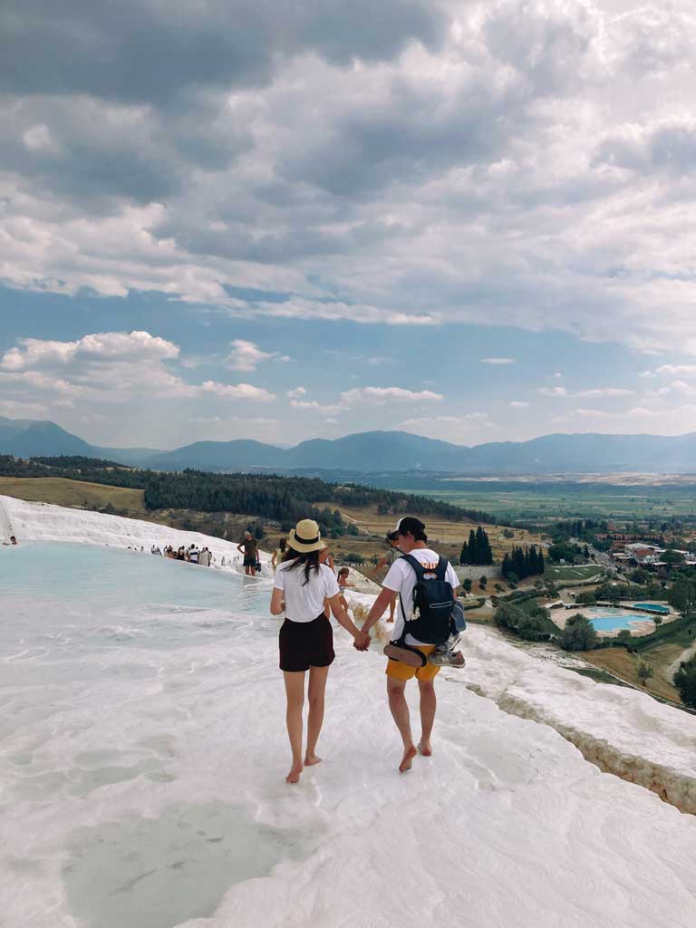 a couple walking on the limestone pools, holding hands