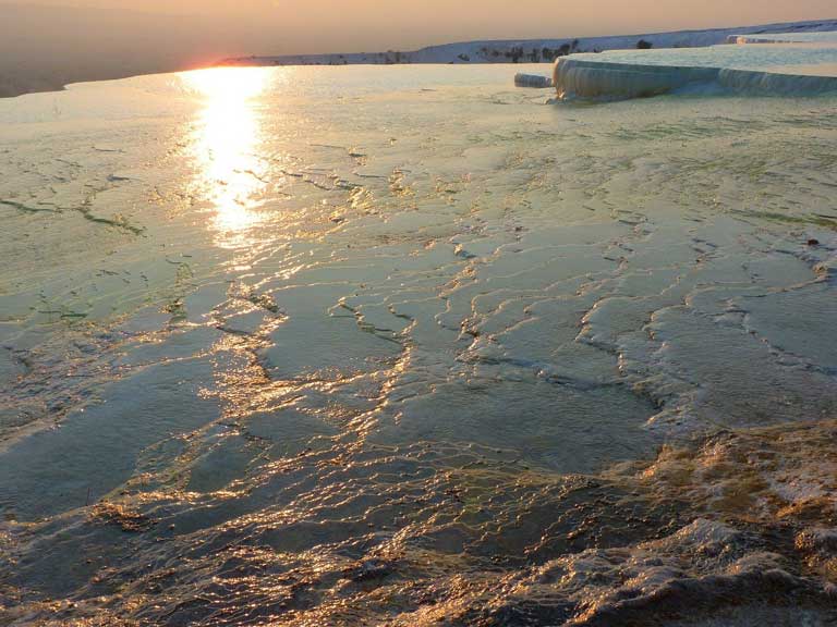 sunset with reflections on limestone pools in Pamukkale