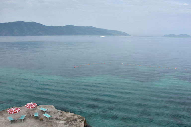 Vlore place near the sea with blue sun loungers and red umbrellas 