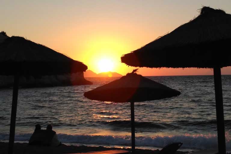 a couple sitting on matala beach watching the sunset