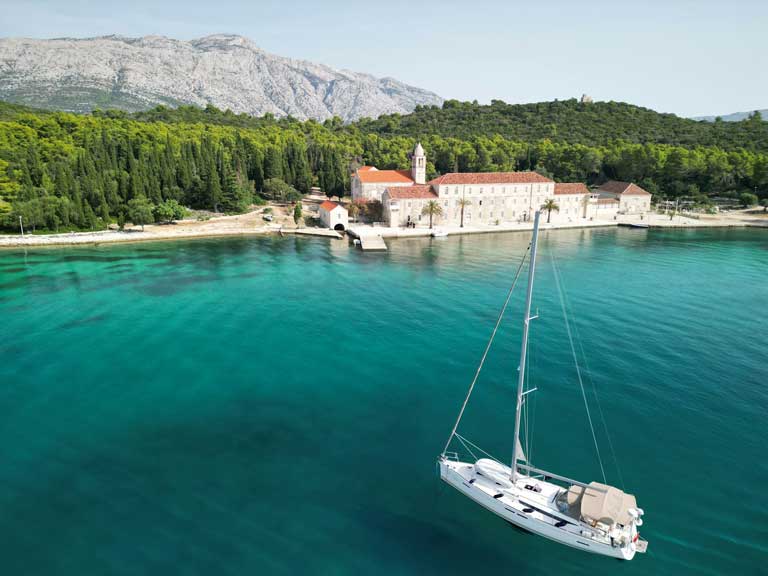 Korcula Island in the background with body of water and a white boat upfront