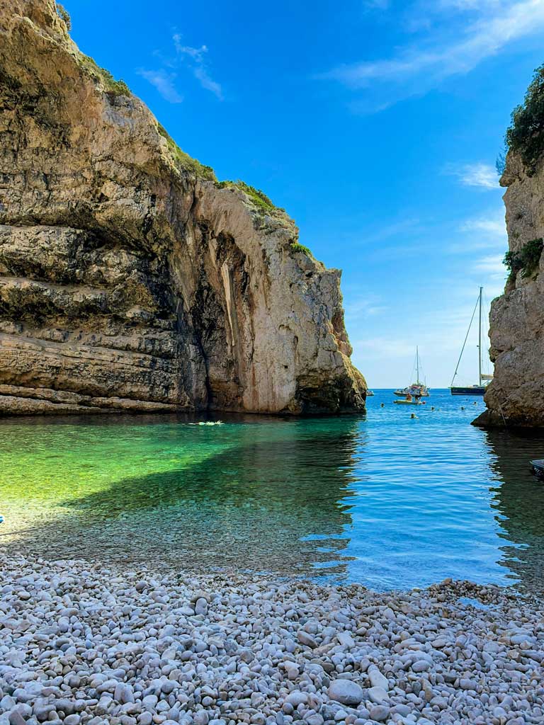 Stiniva bay with pebbles beach, people swimming and yachts