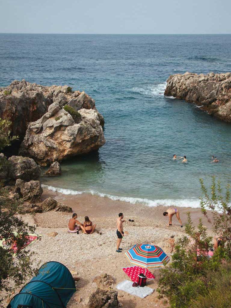 Aquarium Bay in Jale, Albania with people swimming and sitting on the beach